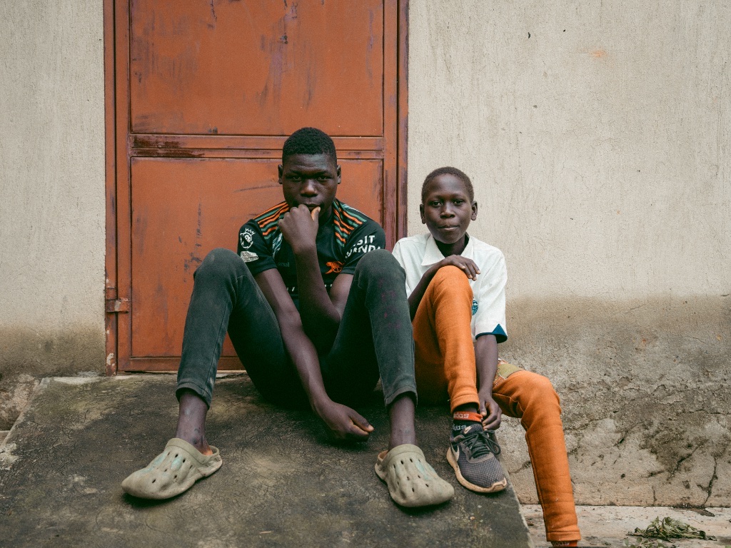 Two children seated by an orange door