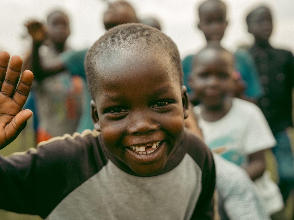 A smiling child waving to the camera